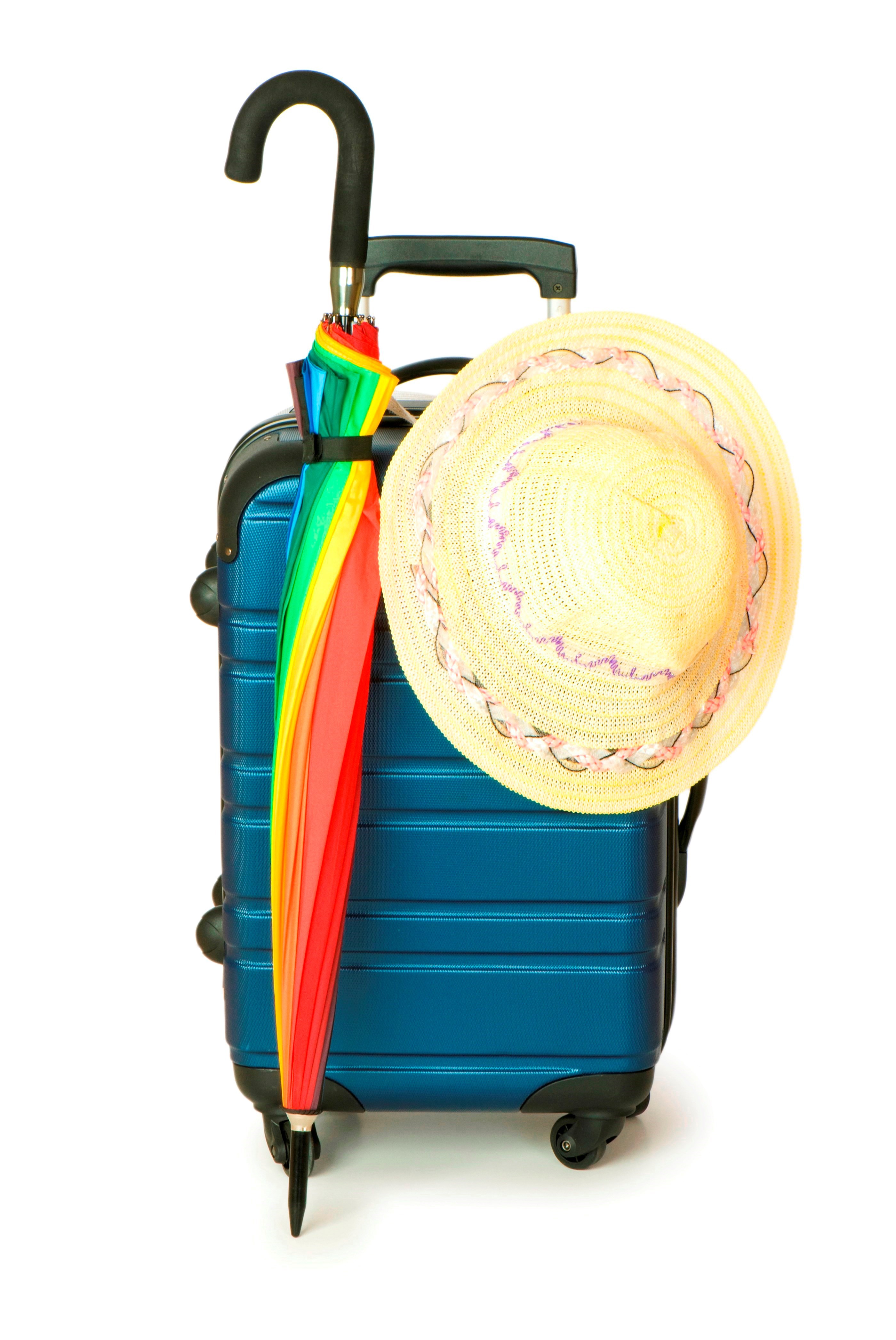 På billedet er en blå kuffert, en regnbuefarvet sammenslået paraply og en stråhat